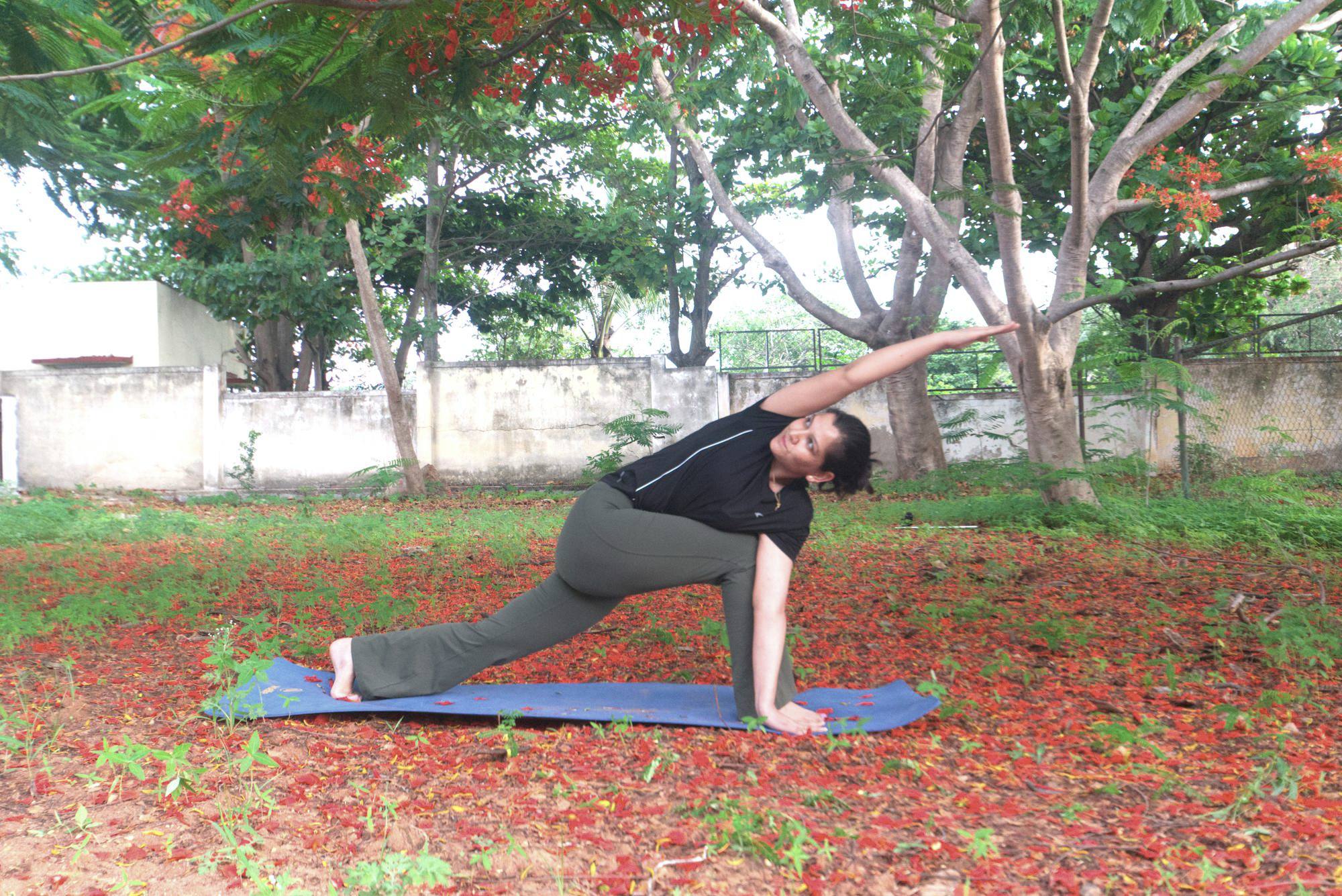 Yoga instructor in a lunging side-stretch pose outdoors
